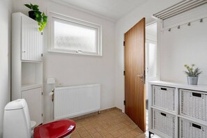 Habitación pequeña y limpia con inodoro, radiador, puerta de madera y cajas de almacenamiento.