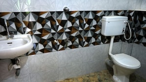 A bathroom with a sink, toilet, and patterned wall tiles.