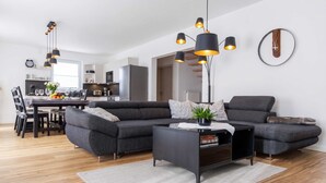 Ein modernes Wohnzimmer mit einem Ecksofa, einem Couchtisch und Pendelleuchten.