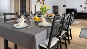 Ein moderner Essbereich mit einem rechteckigen Tisch, gedeckt für sechs Personen, schwarzen Stühlen und einer zentralen Vase mit Blumen.