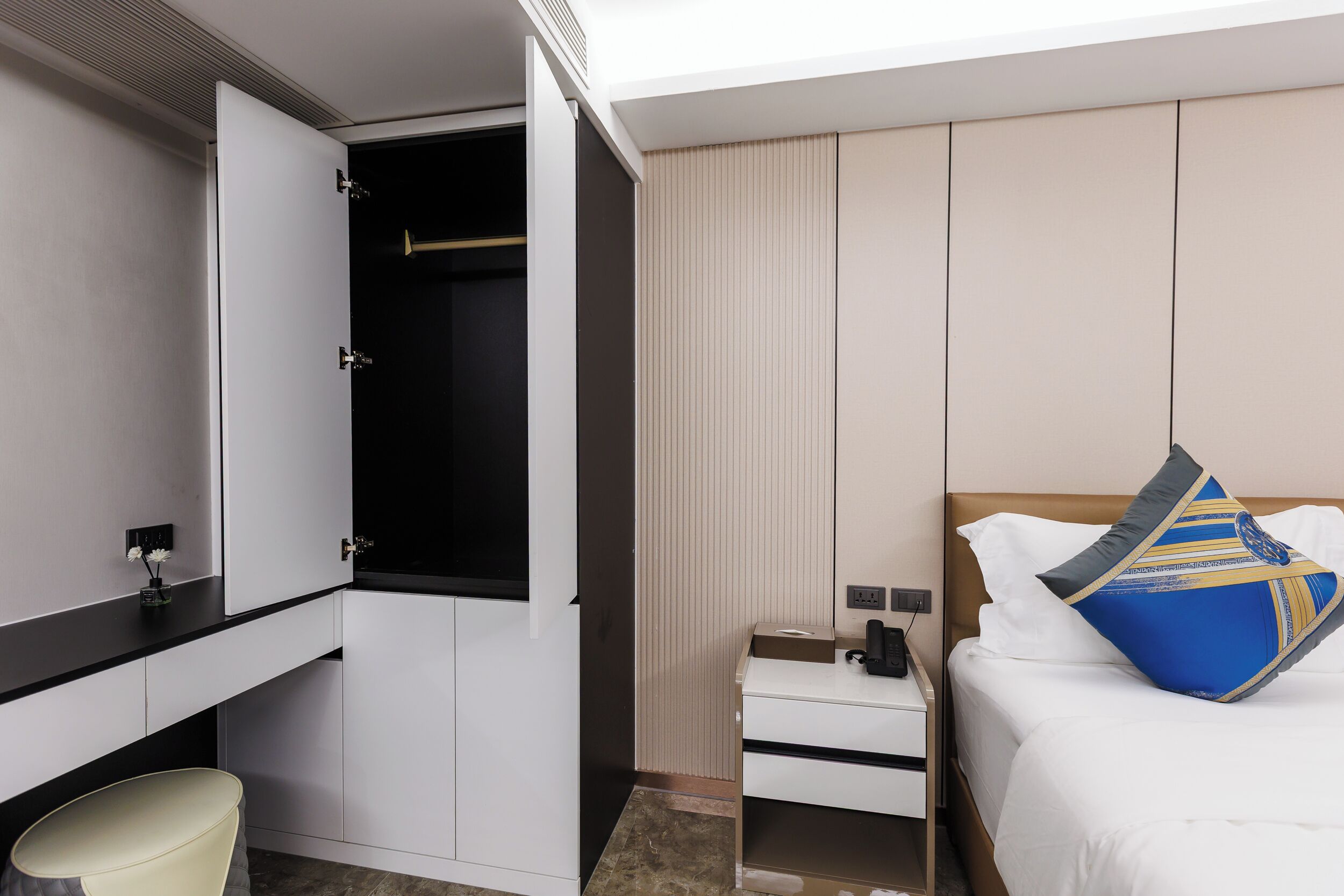 Habitación de hotel con cama, mesita de noche, armario y una pequeña zona de estar.