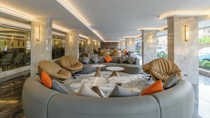 A modern lounge area with seating and tables, marble columns, and a view of the outdoors. - MARQUIS HOTEL (Bangkok)