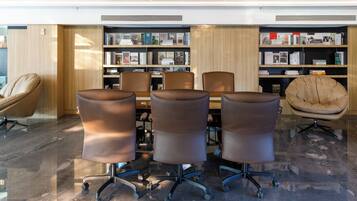 A modern library with a marble floor, leather chairs, and bookshelves.
