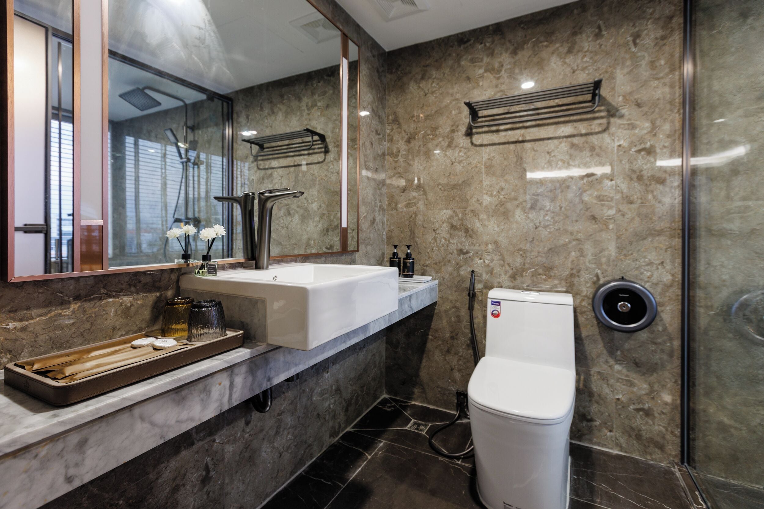 Een moderne badkamer met een grote spiegel, een witte wastafel, toilet en douchehoek.