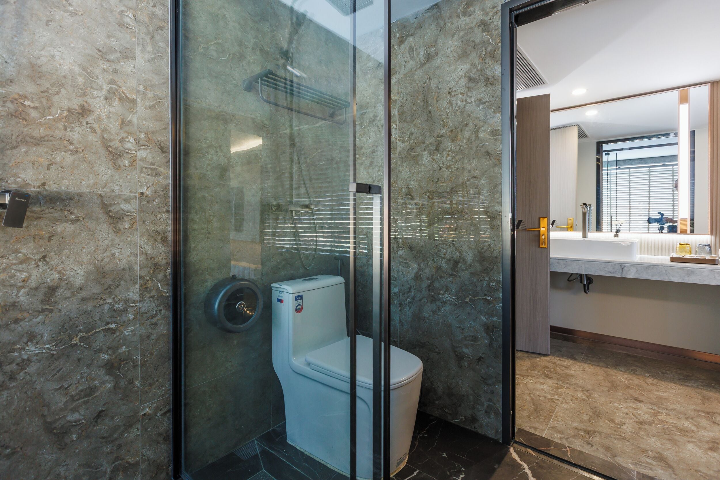 A modern bathroom with a glass-enclosed shower, a toilet, and a vanity with a mirror.