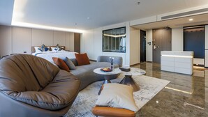 A modern hotel room with a bed, a sofa, a small table, and a reception desk. - MARQUIS HOTEL (Bangkok)