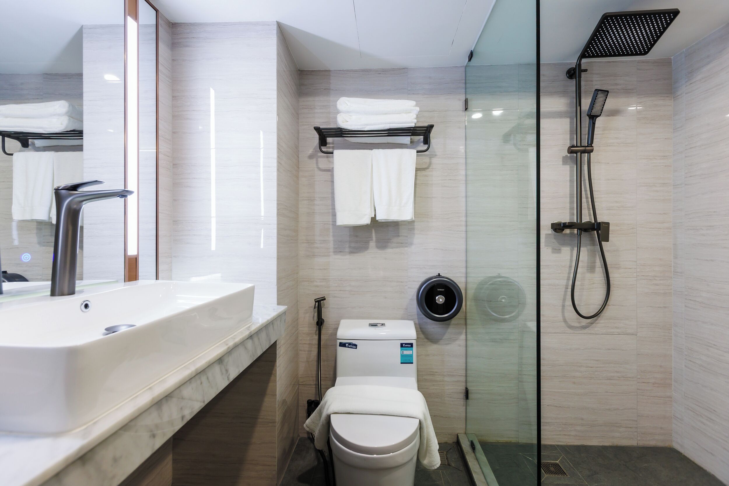 A modern bathroom with a large sink, toilet, and glass-enclosed shower.