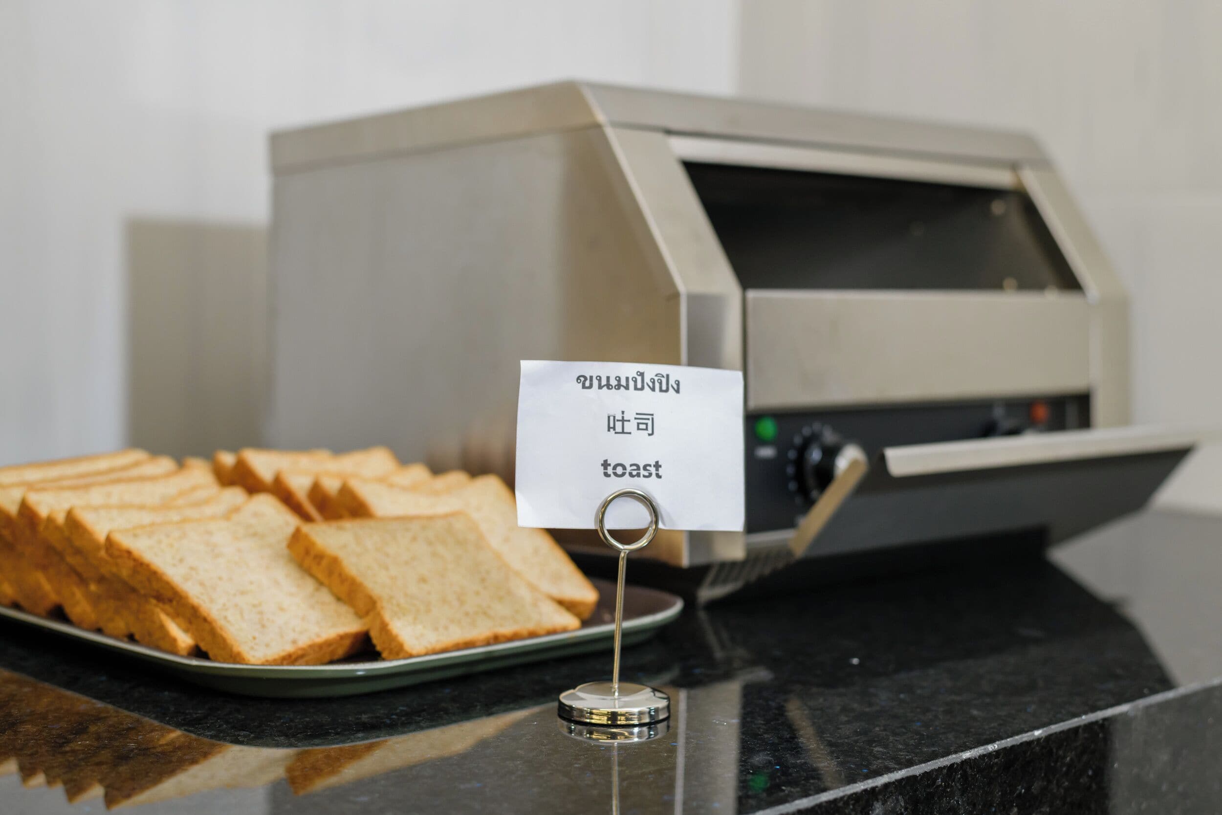 A toaster with a sign indicating it is for toast, and a plate of sliced bread.