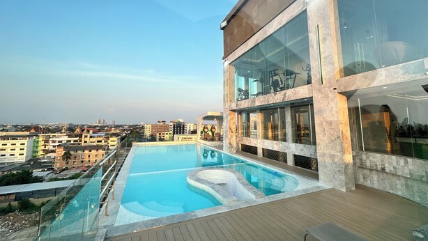 A modern hotel with a rooftop infinity pool, large windows, and a view of the cityscape. - MARQUIS HOTEL (Bangkok)
