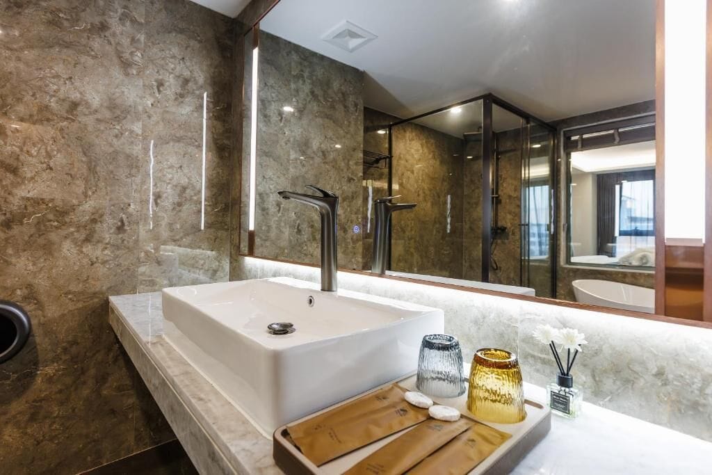 A modern bathroom with a large bathtub, a mirror, and a vanity with toiletries.