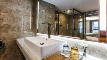 A modern bathroom with a large bathtub, a mirror, and a vanity with toiletries.