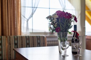 Ein Tisch mit einer Blumenvase, einer Weinflasche und zwei Weingläsern.