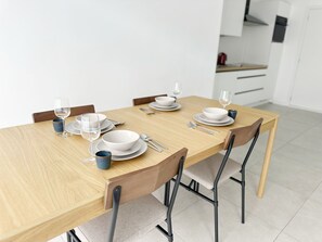 A dining table set with white plates, bowls, and cutlery, accompanied by glasses and a blue mug. - Central 1BR With 1LR Apt Great Location (Ghent)