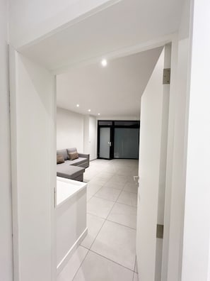 Un interior moderno con un sofá, una mesita y una puerta corredera que da a otra habitación.