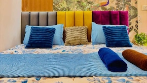 A bedroom with a bed, pillows, a headboard, and a wall mural.