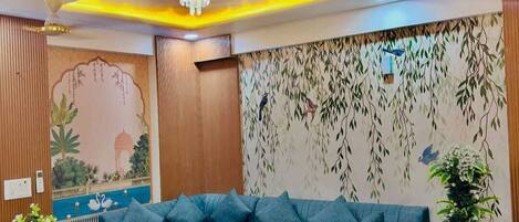 Una sala de estar moderna con un sofá seccional, una mesa de centro de madera y un mural decorativo.