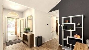 Ein moderner Flur mit Holzboden, einer Bank, einem Konsolentisch mit Pflanzen, einem schwarzen Lautsprecher und einer weißen Konsole mit Regalen an einer dunklen Wand.