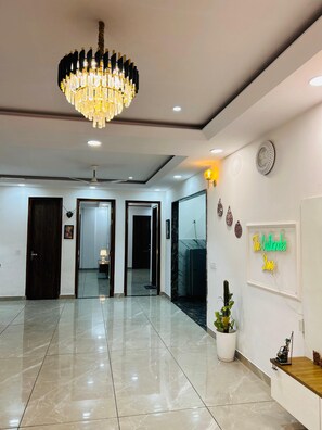 Un hall d’entrée spacieux, agrémenté d’un lustre, d’un comptoir de réception et d’une enseigne lumineuse au néon.