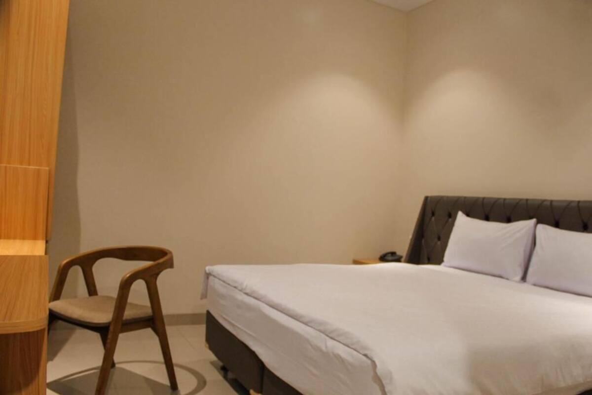 A bedroom with a bed, a chair, and a nightstand.