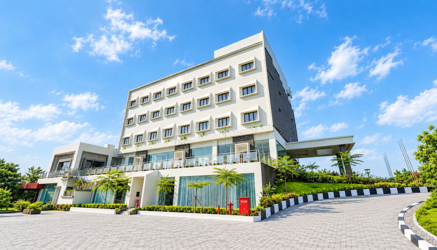 Un hotel moderno con techo plano, varios balcones y un jardín ajardinado.