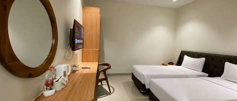 A hotel room with two beds, a desk with a chair, a large mirror, and a television mounted on the wall.