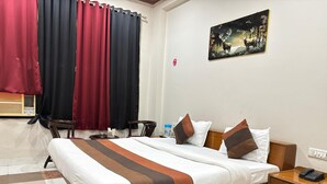 Una habitación de hotel con una cama, mesita de noche y un cuadro en la pared.
