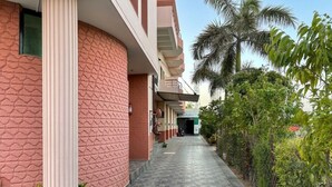 Un pasillo de hotel con suelo de baldosas, una columna, plantas en macetas y una palmera.