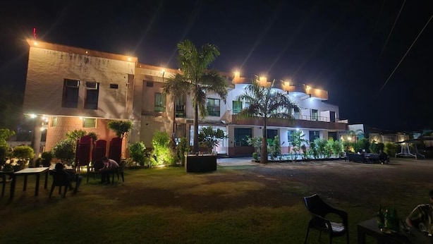 Un edificio de varios pisos, con terraza al aire libre y palmeras.
