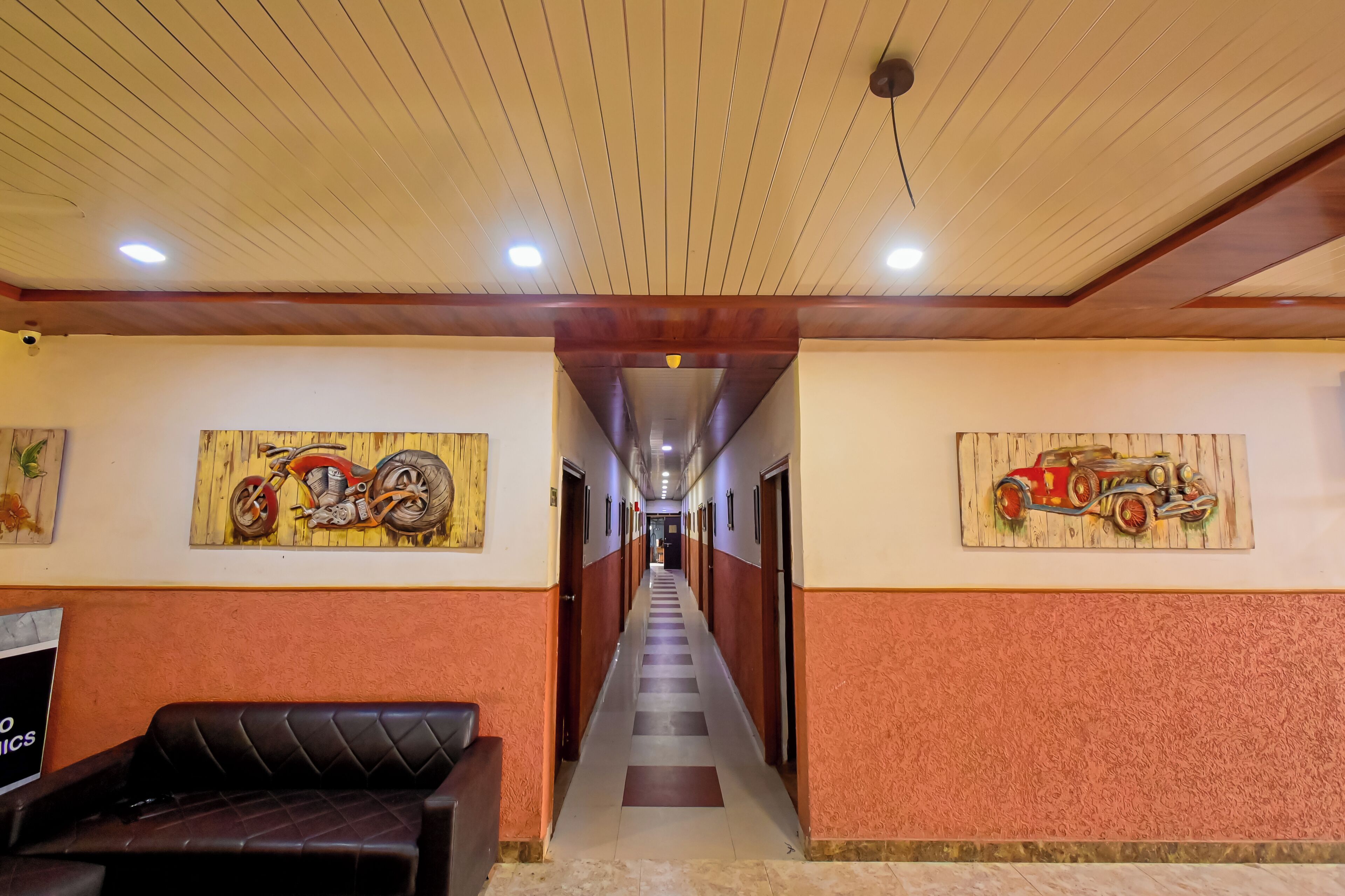 Un pasillo de hotel con suelo a cuadros, una recepción y obras de arte en las paredes.