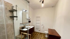 Ein modernes Badezimmer mit Duschkabine aus Glas, einem Holzwaschtisch, einem weißen Waschbecken und einer Toilette.