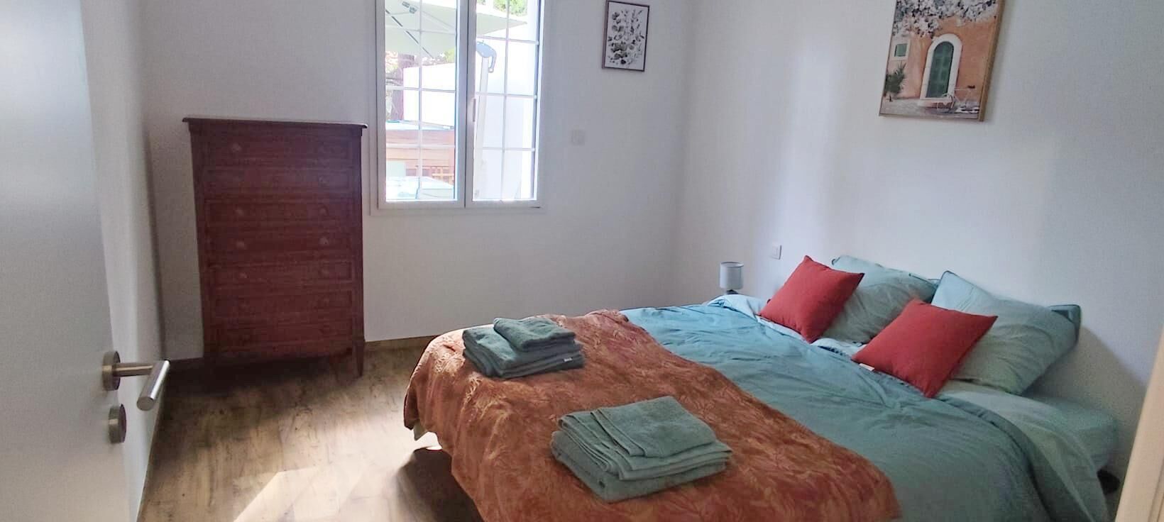 Ein Schlafzimmer mit Bett, Kleiderschrank, Fenster und einem Bild an der Wand.