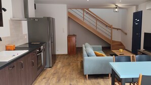 Eine moderne Küche mit Einbauofen, ein Essbereich mit Tisch und Stühlen, eine Sitzecke und eine Treppe, die zu einer weiteren Ebene führt.
