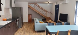 Eine moderne Küche mit Einbauofen, ein Essbereich mit Tisch und Stühlen, eine Sitzecke und eine Treppe, die zu einer weiteren Ebene führt.