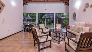 Eine geräumige Terrasse mit Holzmöbeln, einem Deckenventilator und Blick auf einen Garten.