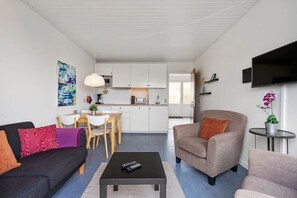 Un salon moderne comprenant un canapé, un fauteuil, une table basse et un coin repas avec une table et des chaises.