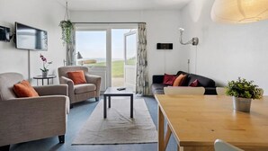 Een moderne woonkamer met een bank, fauteuils, een salontafel en een televisie.