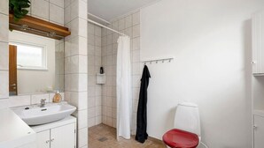 Een badkamer met een wit wastafel, toilet, douchegordijn en spiegel.