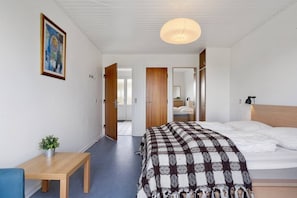 A modern bedroom with a bed, bedside table, and a hanging light fixture.