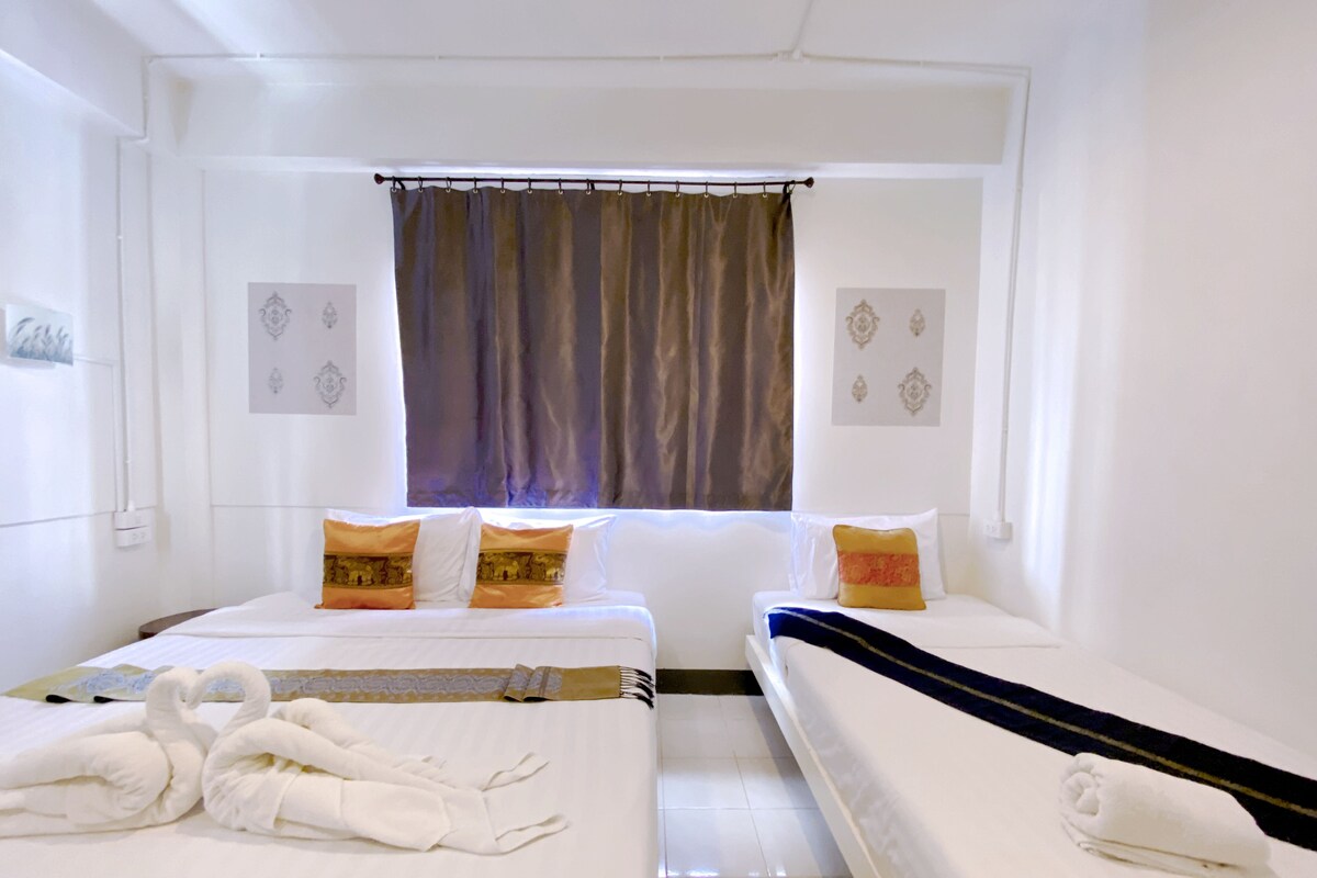 Ett hotellrum med två sängar, ett fönster med gardiner och dekorationer på väggarna.