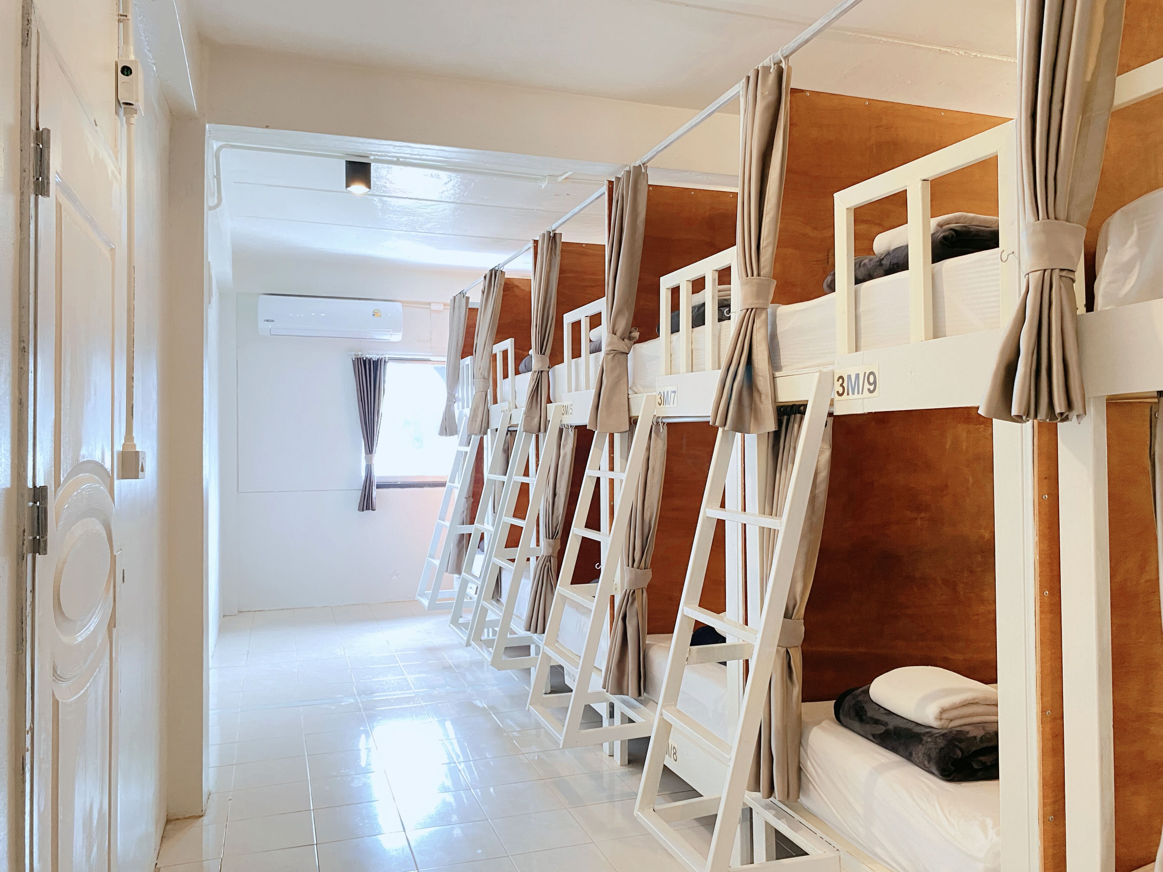 A hotel room with bunk beds, a white door, and a window with curtains.