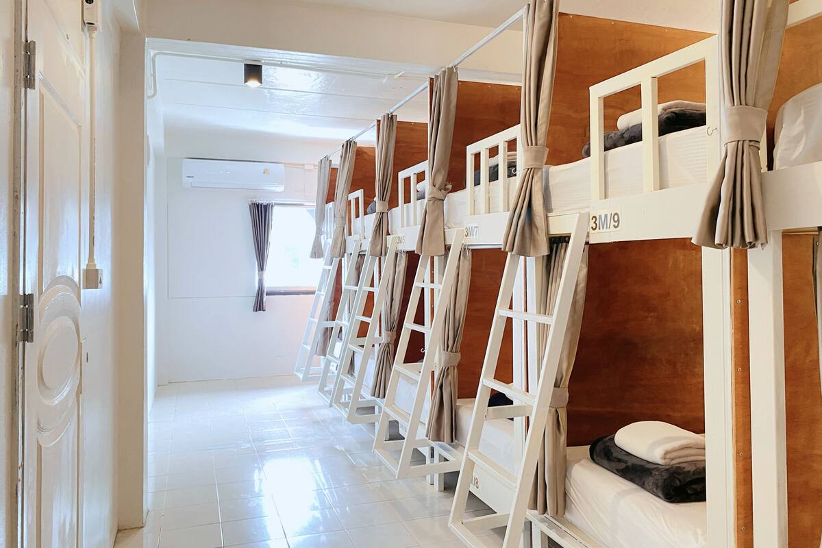 A hotel room with bunk beds, a white door, and a window with curtains.