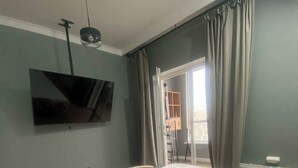 Un dormitorio con una cama grande, un televisor de pantalla plana montado en la pared y vistas al exterior a través de una puerta corrediza.