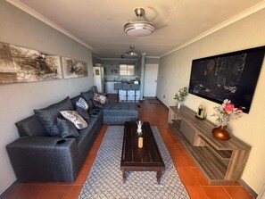 Una sala de estar con sofá, mesa de centro, chimenea y televisor montado en la pared.