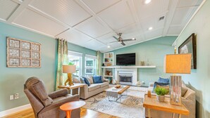 A living room with a sofa, armchair, coffee table, and television. - Coastal Group Getaway Near Three Sisters Springs (Crystal River)