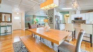A spacious living room with a wooden dining table, comfortable seating, a chandelier, and a kitchen area with modern appliances. - Coastal Group Getaway Near Three Sisters Springs (Crystal River)