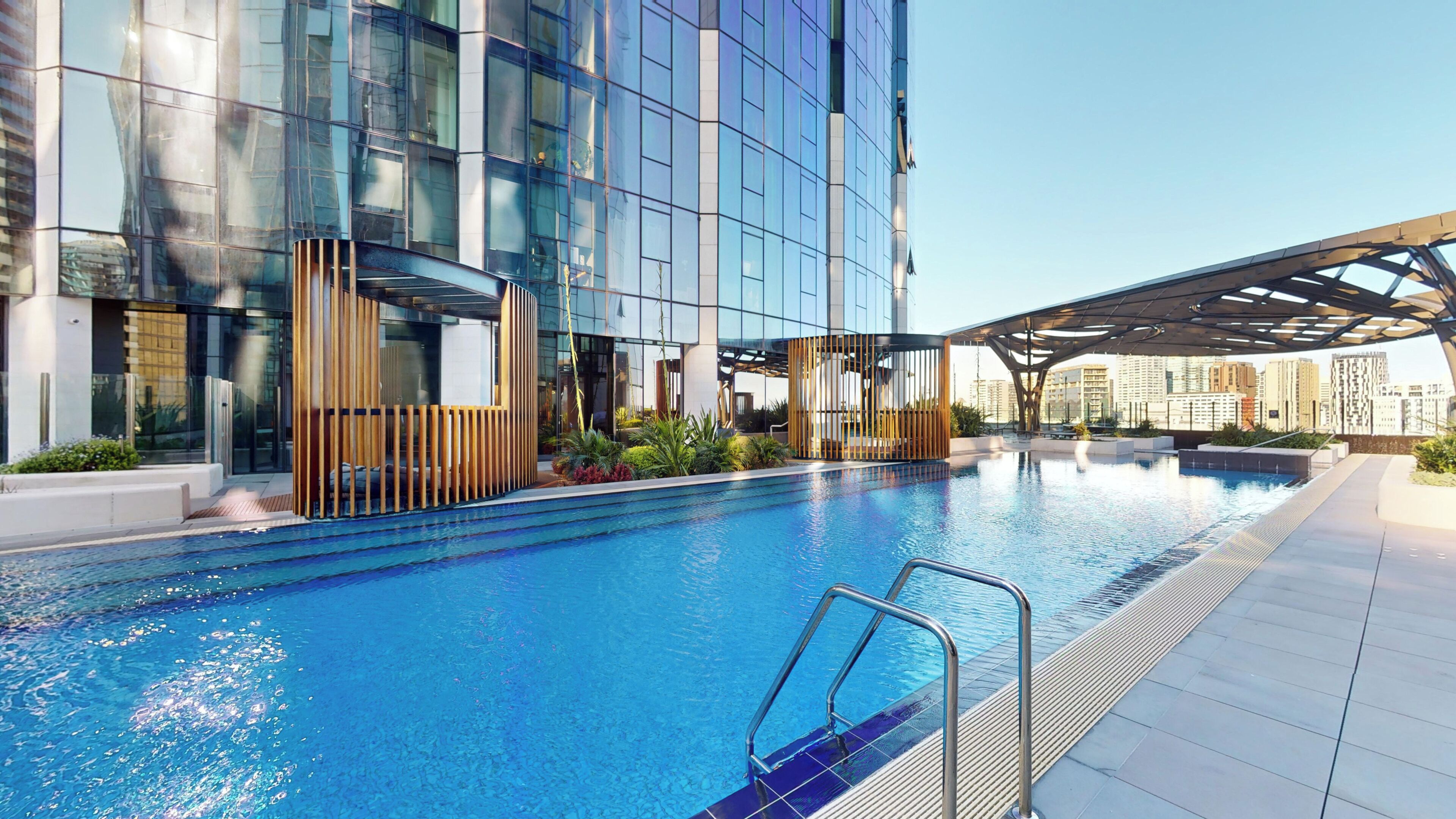 A modern building with a swimming pool, glass facade, and outdoor seating area.