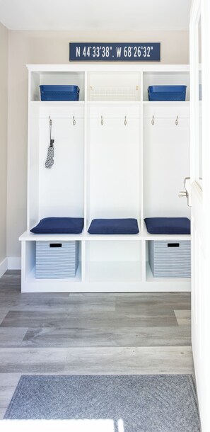 A white storage bench with blue cushions and striped storage bins. - The Fieldstone Getaway (Ellsworth)