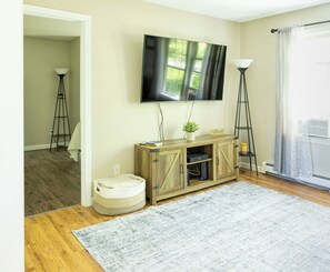 A living room with a television, a wooden cabinet, a floor lamp, and a rug. - The Fieldstone Getaway (Ellsworth)