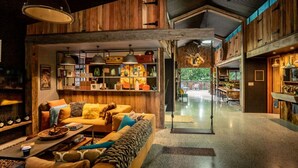 A spacious living area with a sofa, coffee table, and shelves with various items.