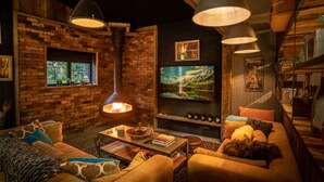 A cozy living room with a brick wall, a fireplace, a television, and a dog.